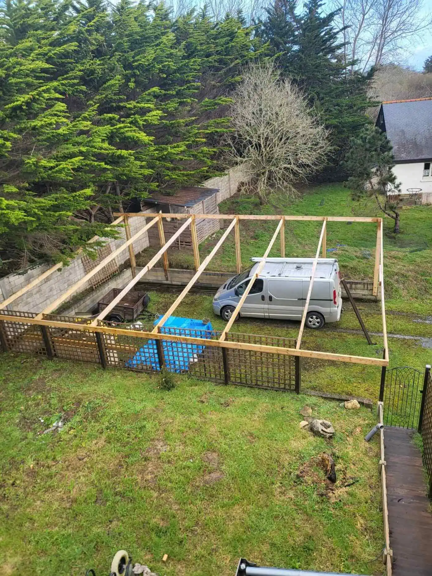Attic construction site with wooden framework and parked van.