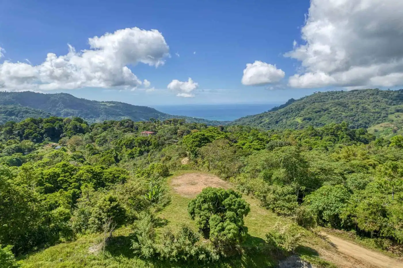 Beautiful lush green tropical mountain scenery with clear blue sky and distant ocean view.