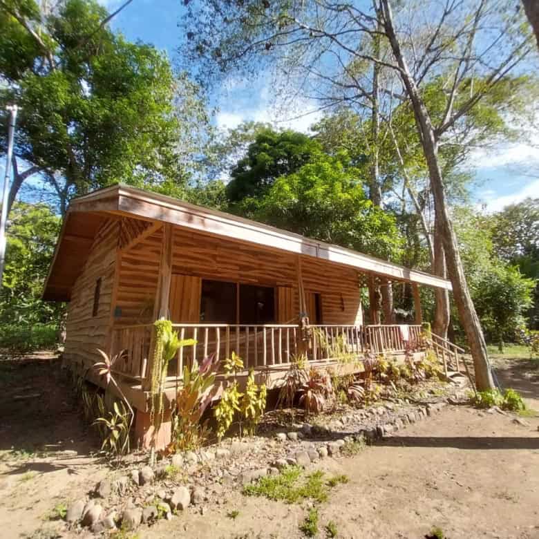 Charming wooden house for sale in Vainilla, Costa Rica, surrounded by lush greenery and nature.