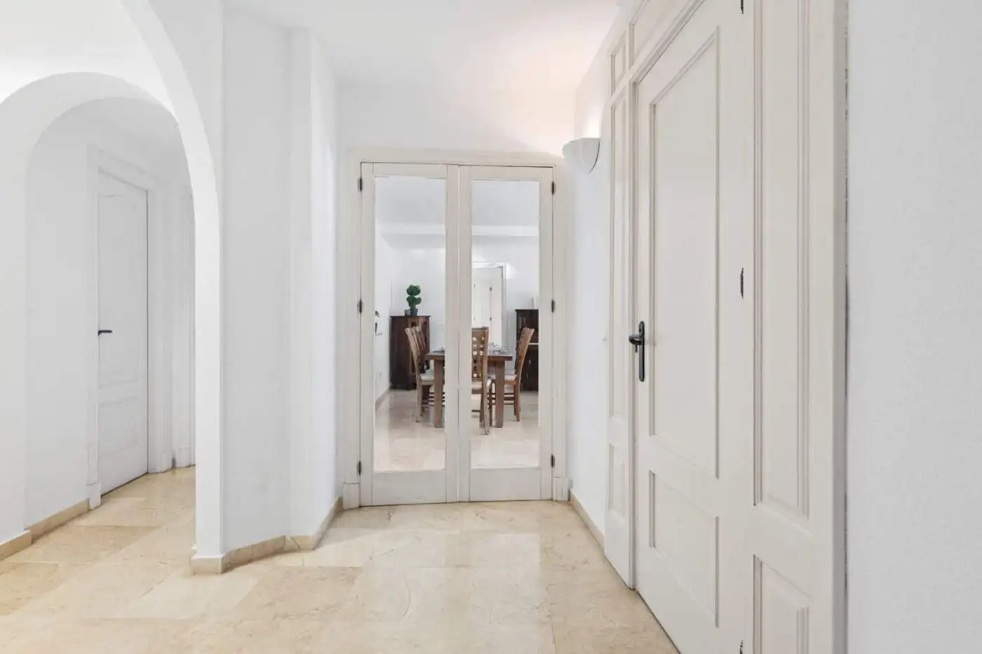 Elegant interior entrance with white walls and double glass doors leading to a spacious living area.