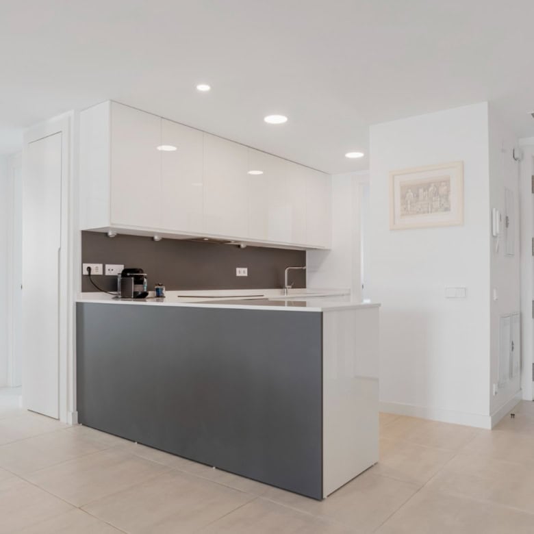 Modern kitchen with sleek white cabinets and gray island in Selwo Estepona penthouse.