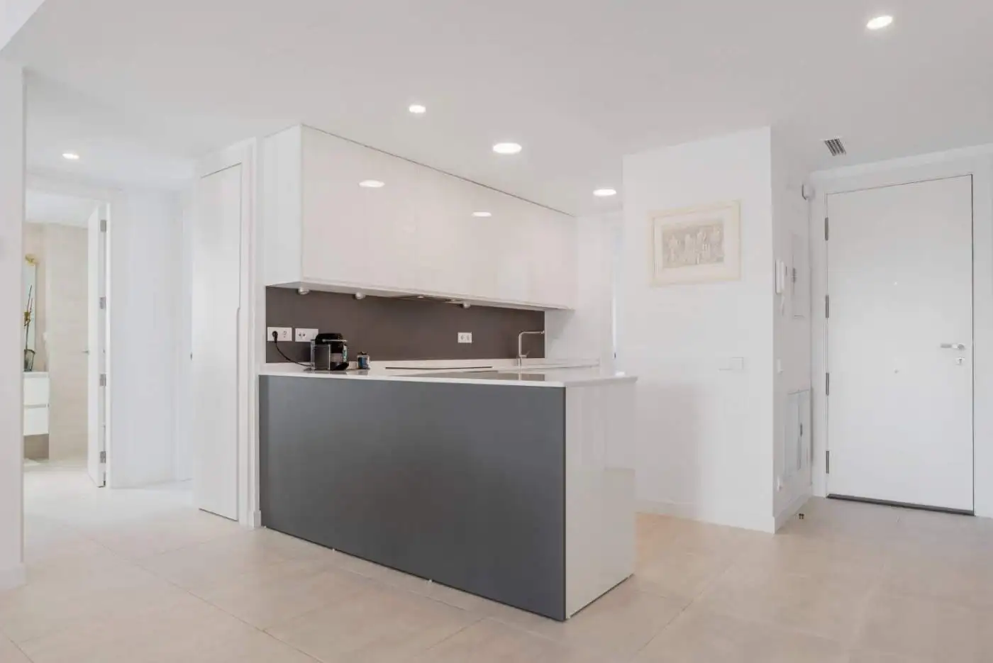 Modern kitchen with sleek white cabinets and gray island in Selwo Estepona penthouse.