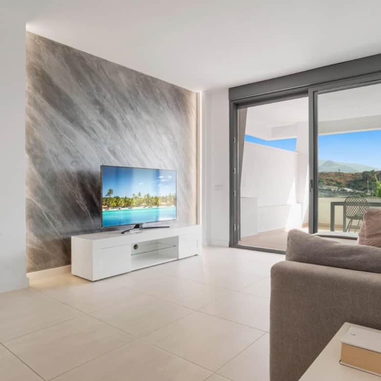 Bright living room with large sliding glass doors opening to a balcony in Selwo Estepona.