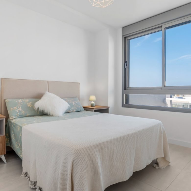 Bright bedroom of a modern 2-bedroom penthouse with large window and sea view in Selwo Estepona.