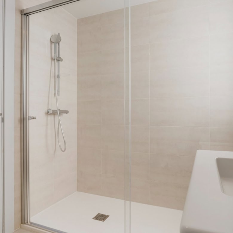 Modern shower with glass enclosure in a spacious bathroom of a 2-bedroom penthouse.