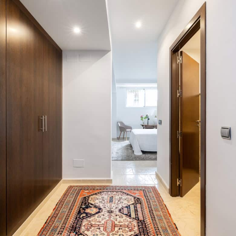 Spacious hallway with wooden wardrobe and decorative rug in a refurbished townhouse.