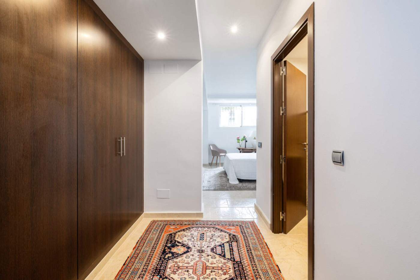 Modern townhouse interior in Brisas del Sur, Andalucia. Spacious hallway with wooden wardrobe and decorative rug in a refurbished townhouse.