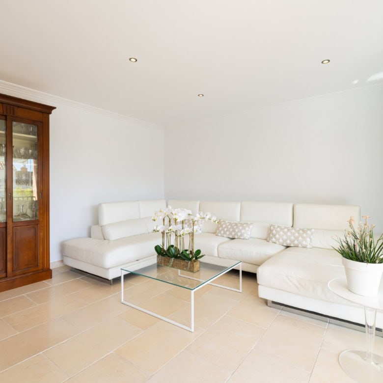Modern living room with white sofa and glass coffee table.