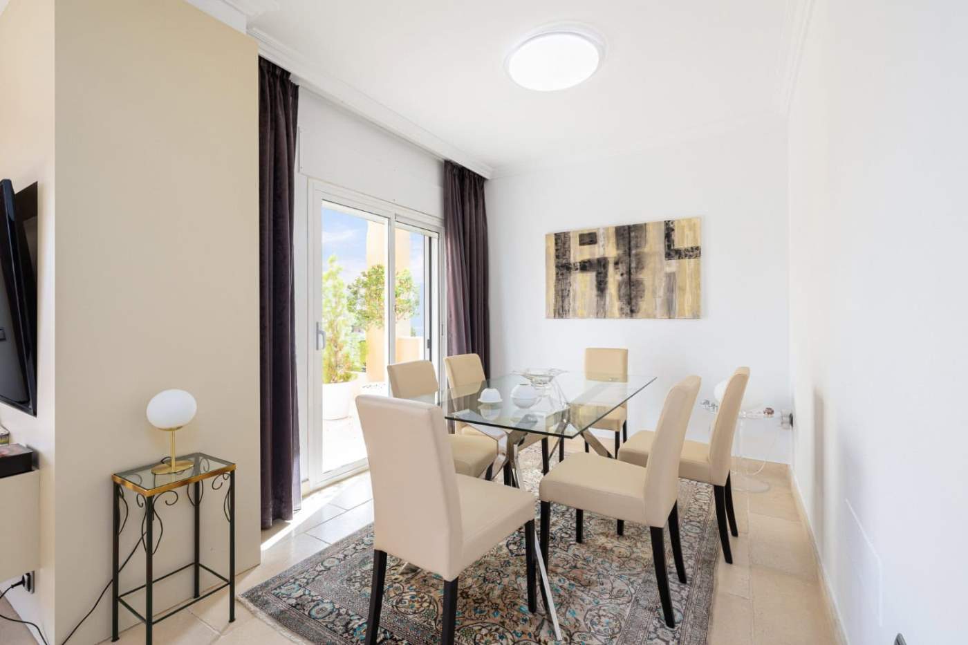 Modern dining room with glass table and beige chairs in refurbished townhouse. Refurbished townhouse dining area with glass table and elegant beige chairs.