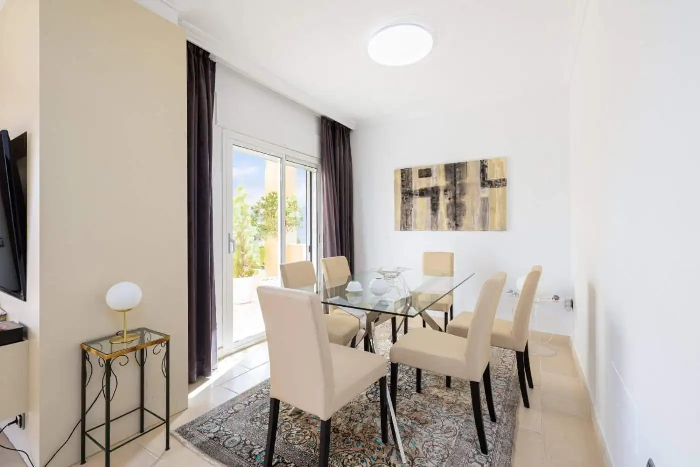 Refurbished townhouse dining area with glass table and elegant beige chairs.