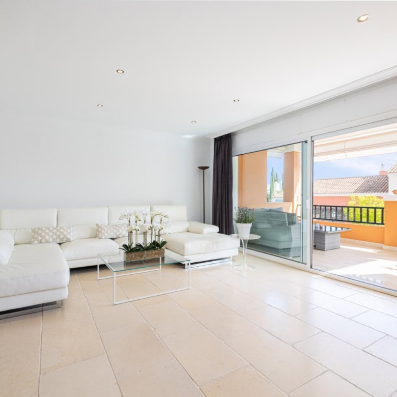 Modern living room with bright, spacious design and large sliding glass doors opening to a sunny ter.