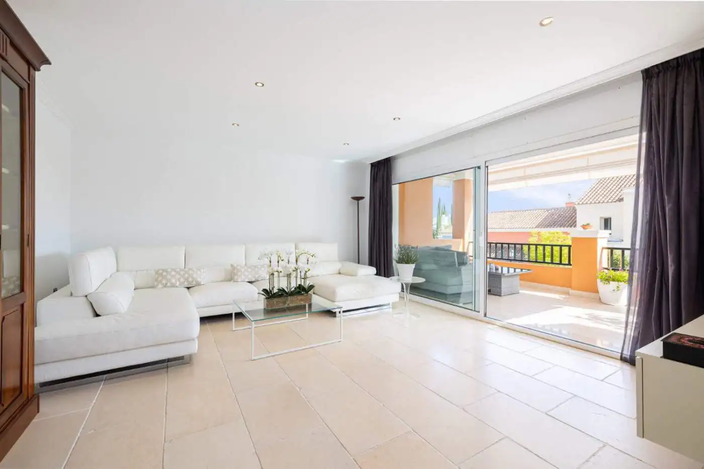 Modern living room with bright, spacious design and large sliding glass doors opening to a sunny ter.