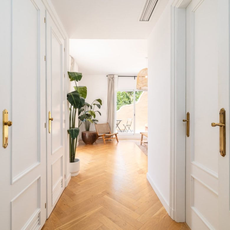 Bright hallway leading to a stylish living area with large windows and panoramic city views.