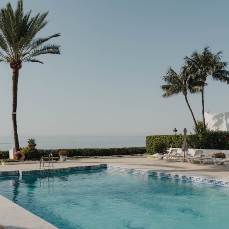 Pool and palm trees at a luxurious Marbella beachfront property.