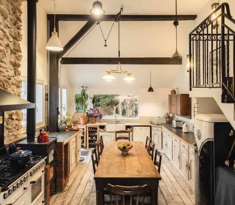 Cozy kitchen of a stone house estate with rustic wooden dining table and modern appliances in La Cel.