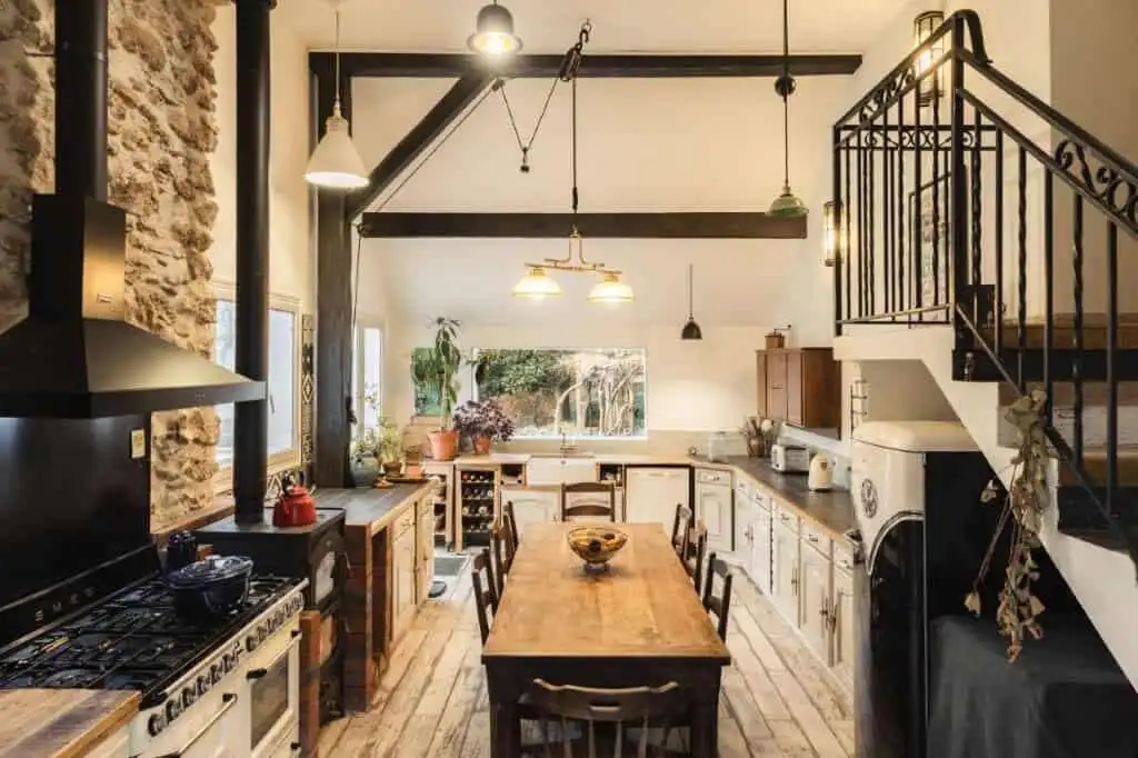 Cozy kitchen of a stone house estate with rustic wooden dining table and modern appliances in La Cel.