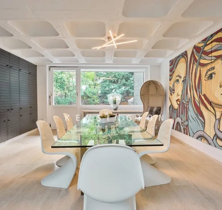Elegant dining room with modern decor and large windows overlooking greenery.