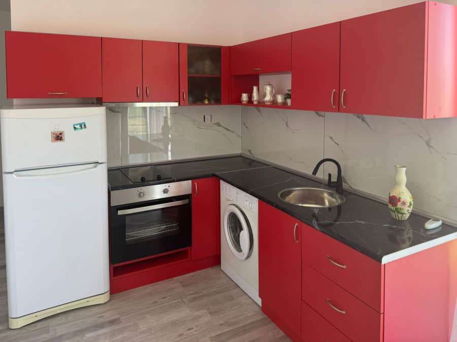 Red kitchen with appliances in Sunny Day 5, ready to move in.