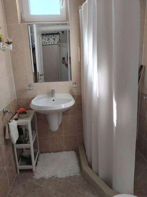 Bright bathroom with sink and shower in modern Sunny Day 5 apartment.