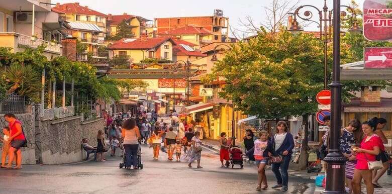 View of a lively street in St. Vlas with shops, people, and trees near Panorama Bay 1, 100m from the.