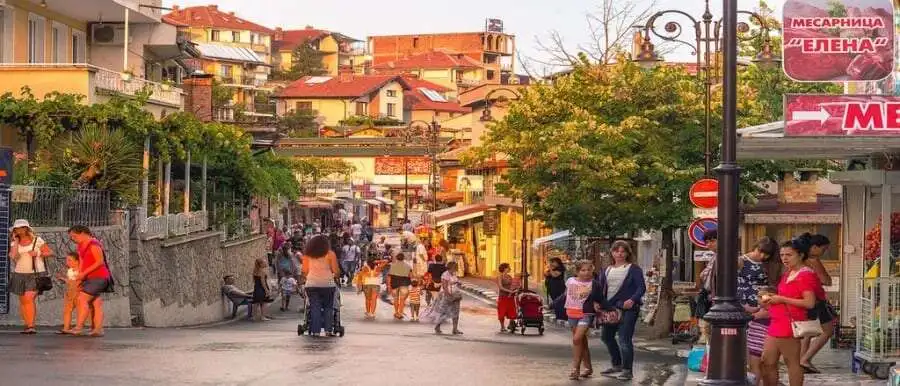 View of a lively street in St. Vlas with shops, people, and trees near Panorama Bay 1, 100m from the.