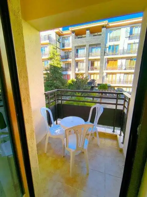 Balcony with white plastic chairs and small table overlooking a modern apartment complex in Sveti Vl.