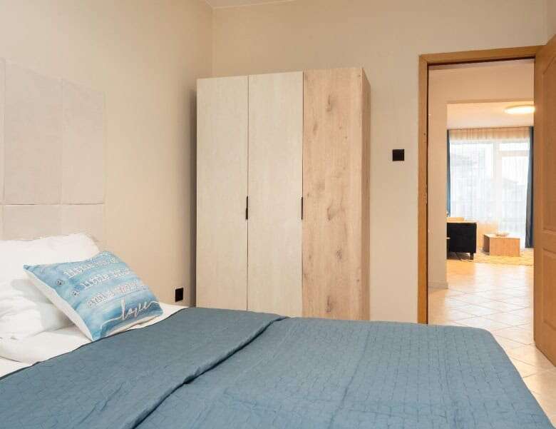 Bedroom with bed, wardrobe, and view into living area in Sunny Beach apartment.