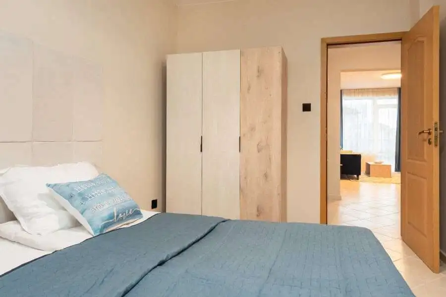 Bedroom with bed, wardrobe, and view into living area in Sunny Beach apartment.