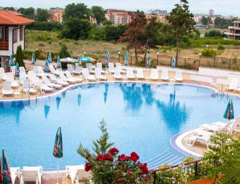Bright outdoor pool area with sun loungers and umbrellas at Gardenia Hills.