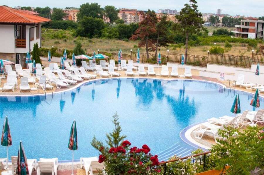 Bright outdoor pool area with sun loungers and umbrellas at Gardenia Hills.