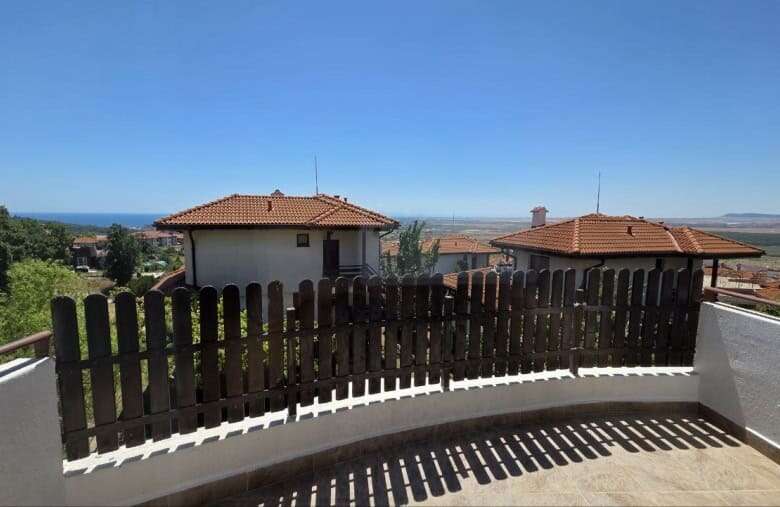 View of a modern villa with a wooden fence and sea in the background in Bulgaria.