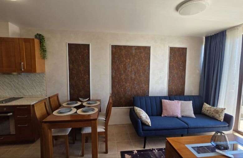 Bright living space featuring a blue sofa, dining area, and balcony overlooking scenic surroundings.
