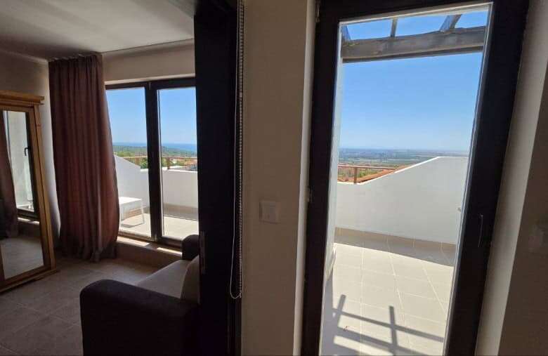 Bedroom with balcony overlooking scenic landscape in Bay View Villas, Kosharitsa, Bulgaria.