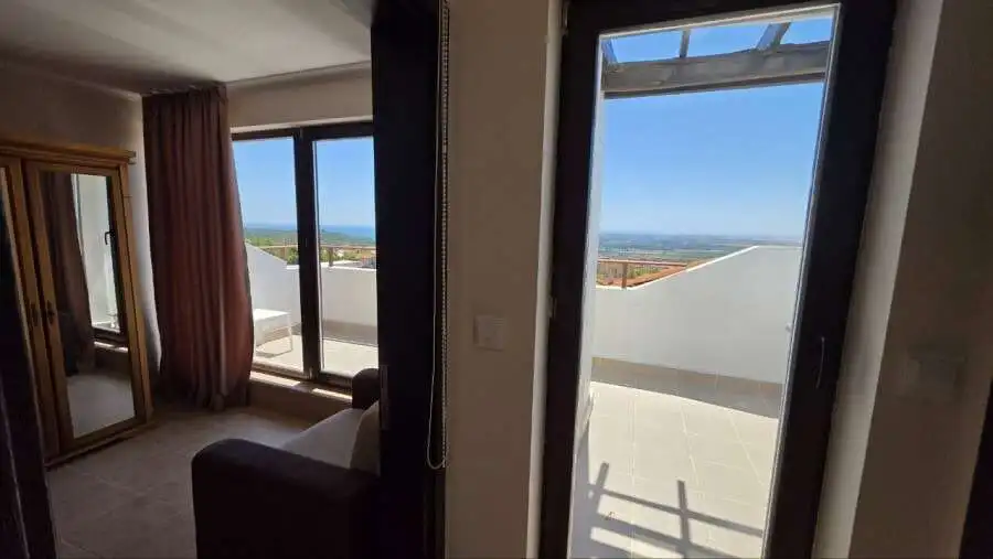 Bedroom with balcony overlooking scenic landscape in Bay View Villas, Kosharitsa, Bulgaria.