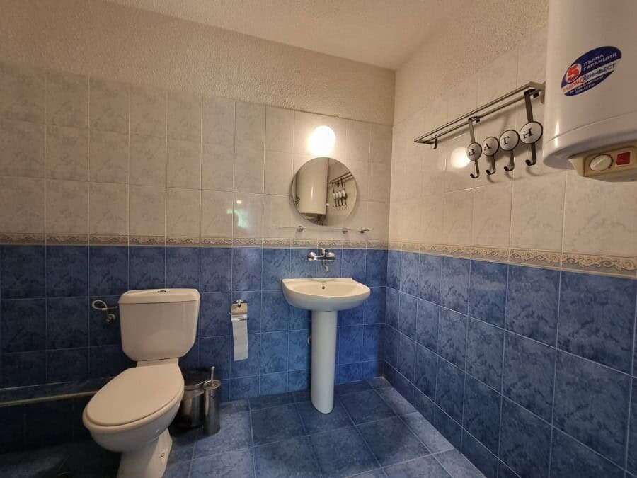 Bathroom with toilet, sink, and water heater in a furnished apartment.
