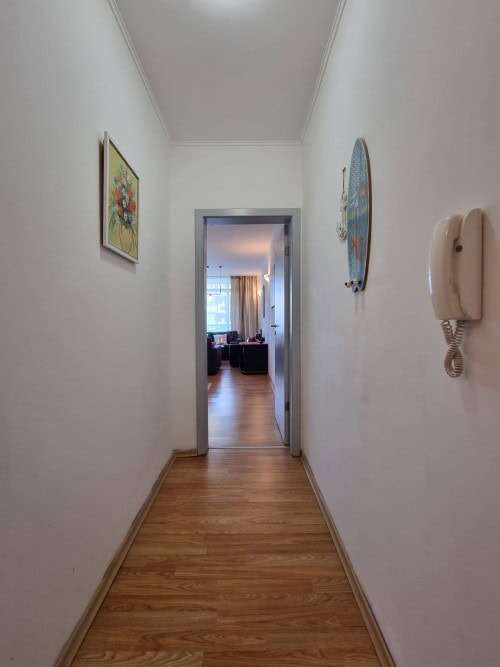 Bright, clean corridor leading to spacious living area with natural light.