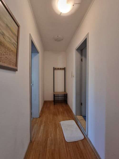 Bright, clean corridor with two doorways and a small bench at the end.