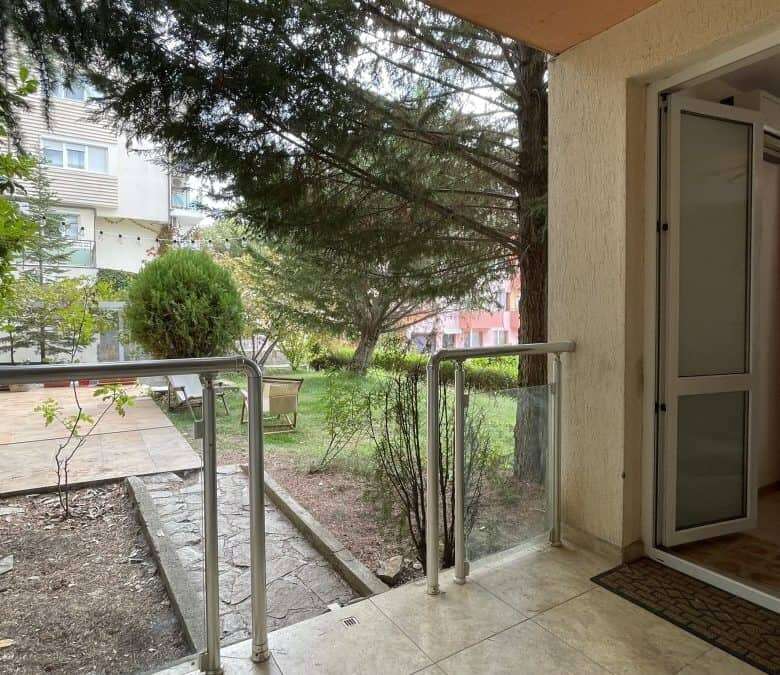 Balcony overlooking lush garden in Sveti Vlas, Bulgaria, with outdoor seating and greenery.