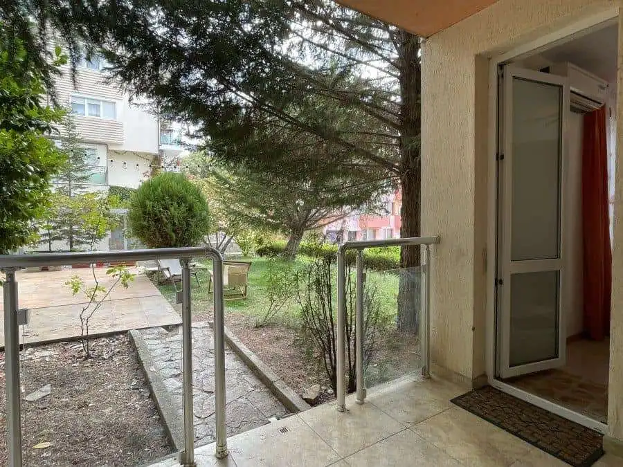 Balcony overlooking lush garden in Sveti Vlas, Bulgaria, with outdoor seating and greenery.