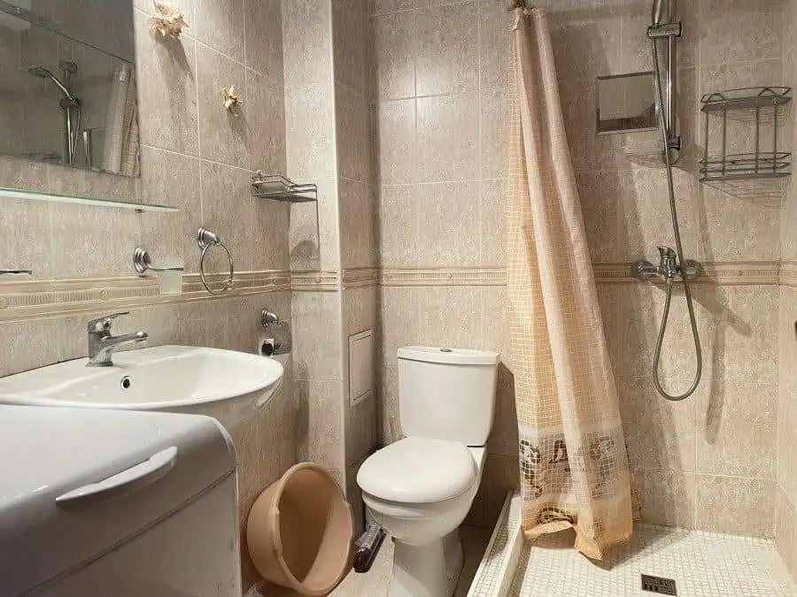 Modern bathroom with shower, toilet, and beige tiles in Sveti Vlas apartment.