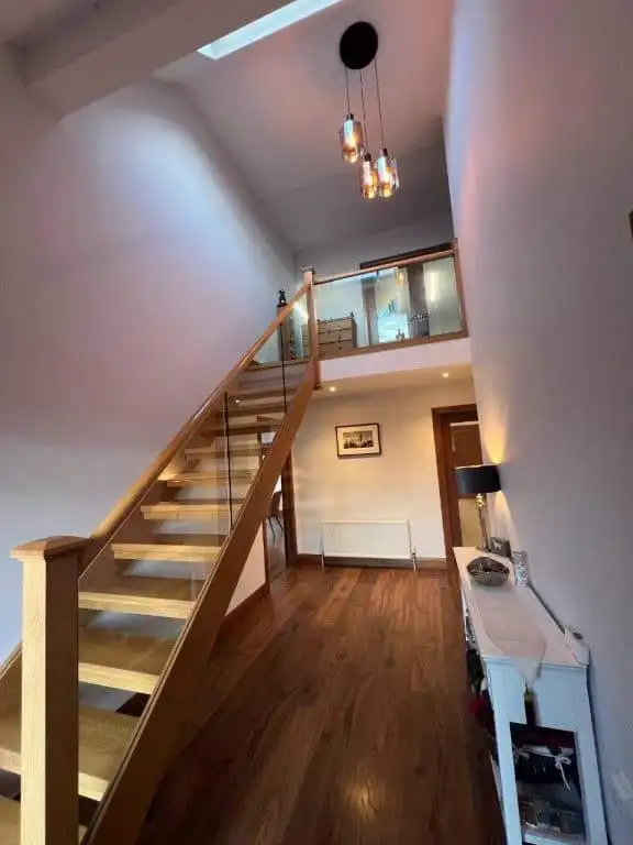 Interior view showcasing a contemporary home with a wooden staircase, high ceiling, and natural ligh.