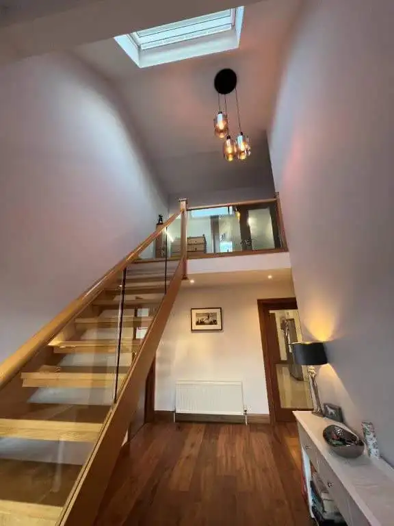 Elegant staircase with glass railing and natural light from skylight.
