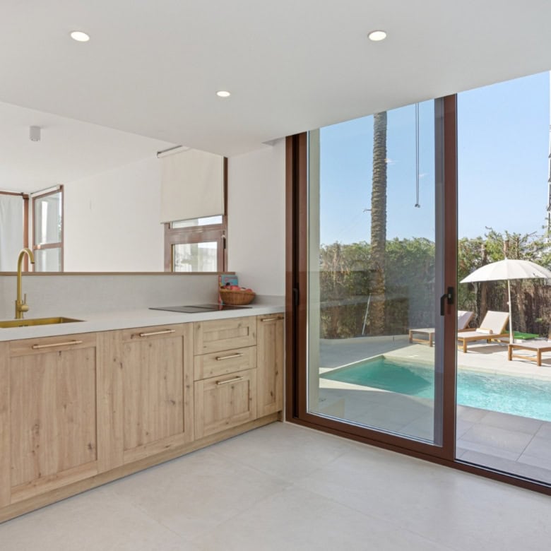 Modern kitchen overlooking private pool and outdoor lounge area.