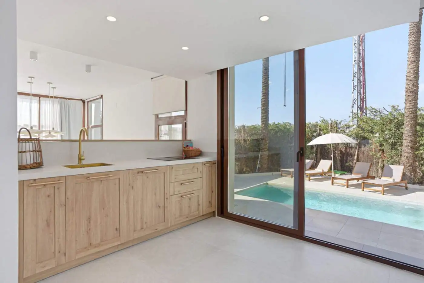 Modern kitchen overlooking private pool and outdoor lounge area.