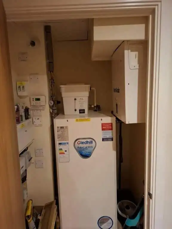 Utility room with washing machine, electrical panels, and storage space in a contemporary apartment.