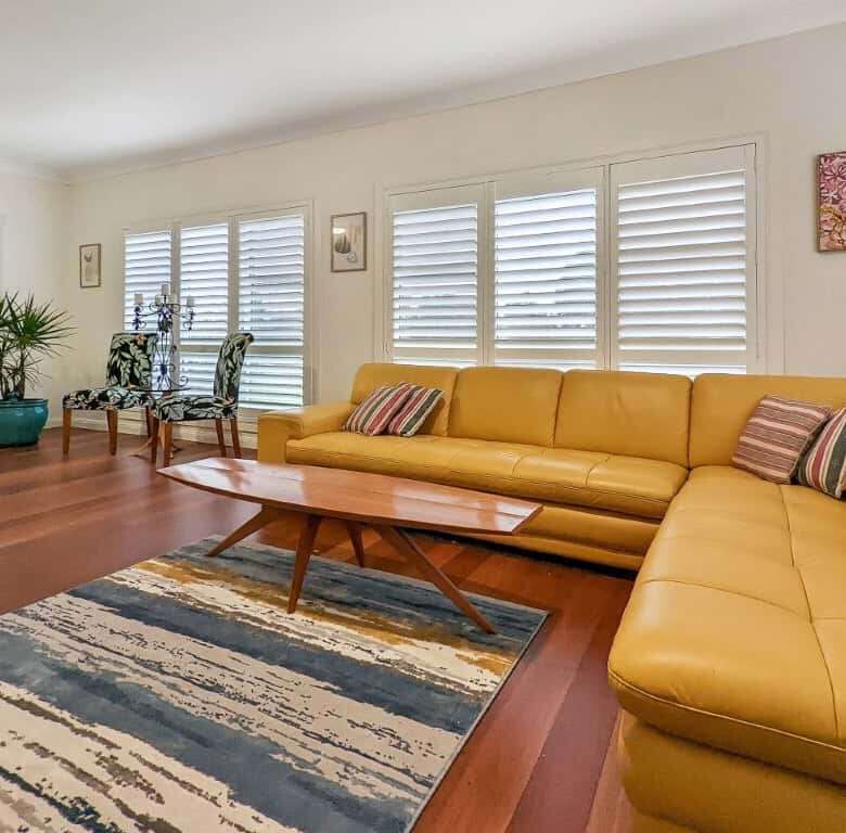 Spacious living room with large windows, modern decor, and a yellow sectional sofa in Broke.