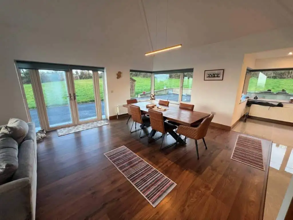 Spacious dining area featuring large windows with scenic countryside views. Modern decor and hardwoo.