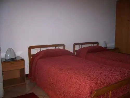 Hotel room with two single beds and wooden headboards near Lake Viverone, Piverone, Italy.