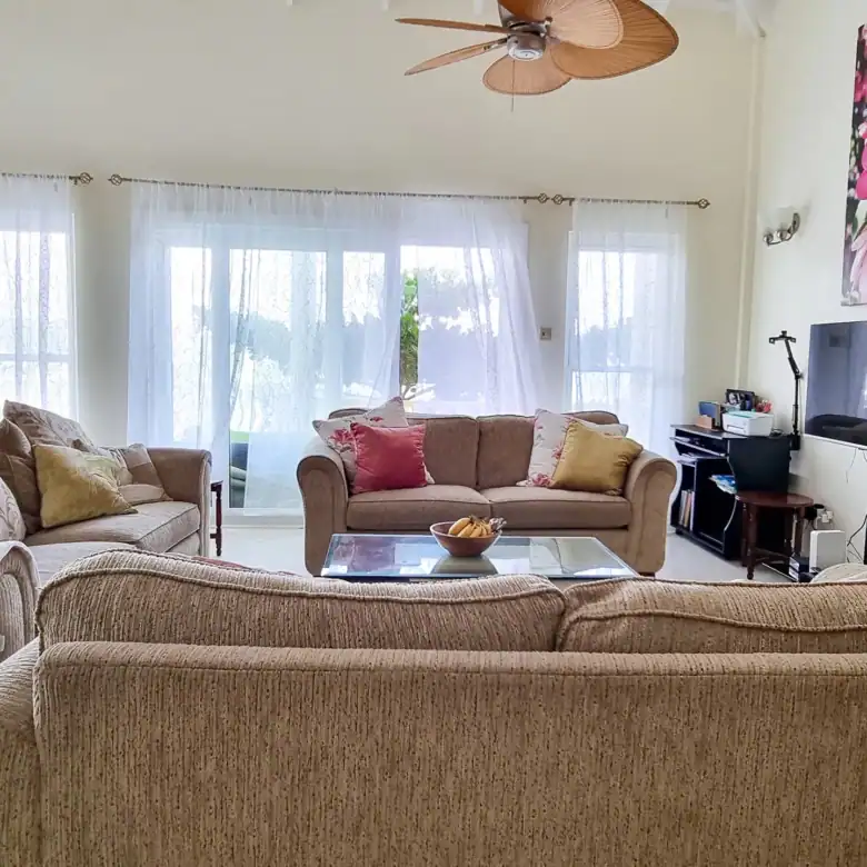 Elegant living room with large windows and comfortable sofas in Saint George, Grenada.
