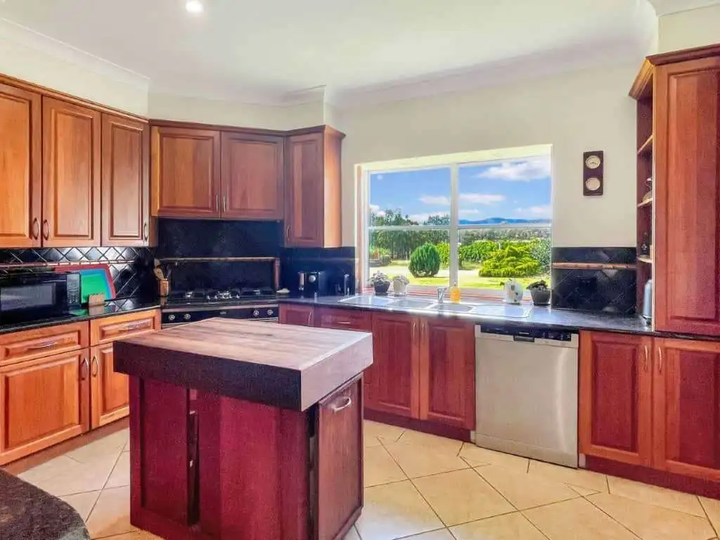 Vineyard Estate Kitchen with Scenic Views Spacious kitchen featuring wooden cabinets and a large window overlooking vineyards and rolling hill.